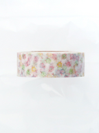 A roll of washi tape with a delicate pastel floral pattern on a white background, photographed against a clean white backdrop.