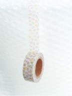 A roll of washi tape with a delicate pastel floral pattern, shown hanging against a textured white background.