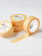 Three rolls of yellow washi tape with black polka dots on a light gray background