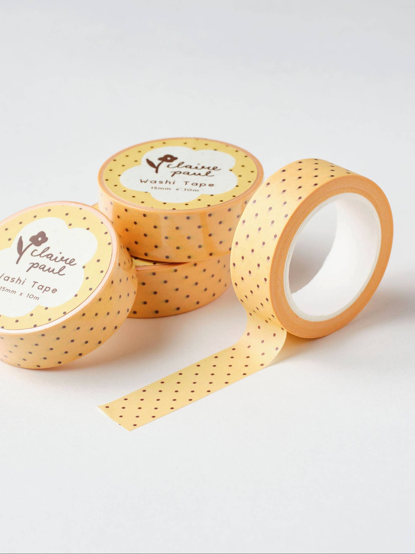 Three rolls of yellow washi tape with black polka dots on a light gray background