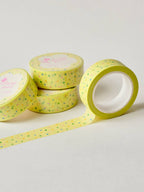 Four rolls of yellow washi tape with a pattern on a light gray background